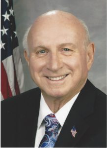 A man in suit and tie next to an american flag.