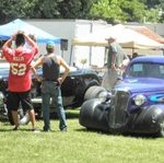 A group of people looking at cars at a car show.