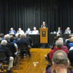 A group of people participating in a mid-term examination at a podium.