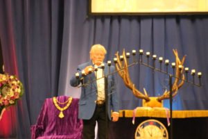 A man standing in front of a stage at the Elks memorial service with antlers.