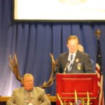 A group of men standing at a podium at an Elks convention.