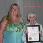 A woman standing next to another person holding a certificate.