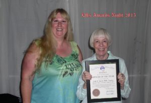 A woman standing next to another person holding a certificate.