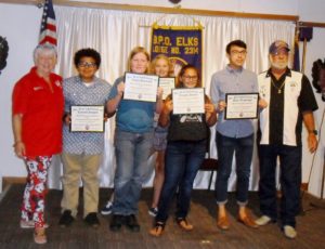 A group of people holding certificates in front of an american flag.