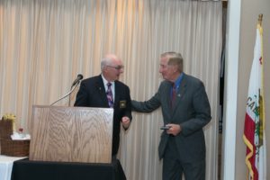 Two men in suits are shaking hands at a podium.