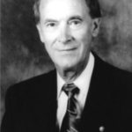A black and white photo of an older man in a suit.