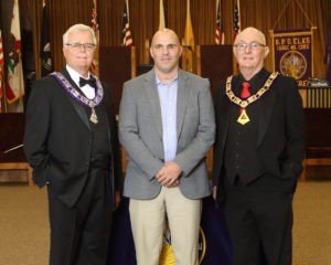 Three men in suits and a purple tie