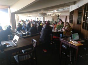 A group of people sitting at tables with laptops.