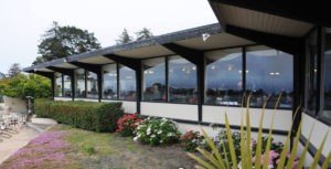 A restaurant with many windows and flowers outside