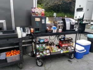 A cart with food on it next to an ice chest.