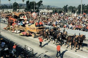 A parade with horses and carriages in the middle of it.