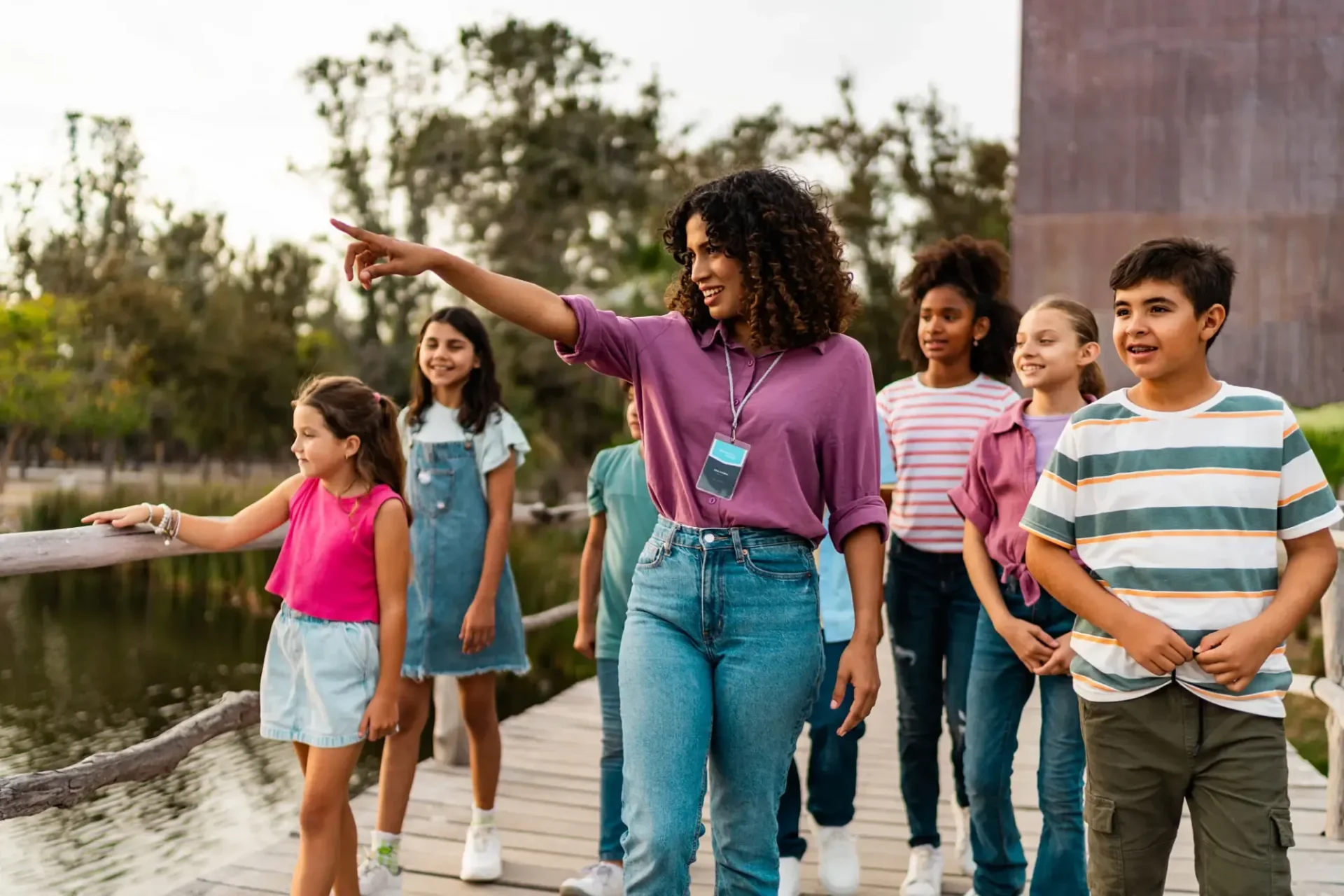 Teacher leading children on boardwalk near pond