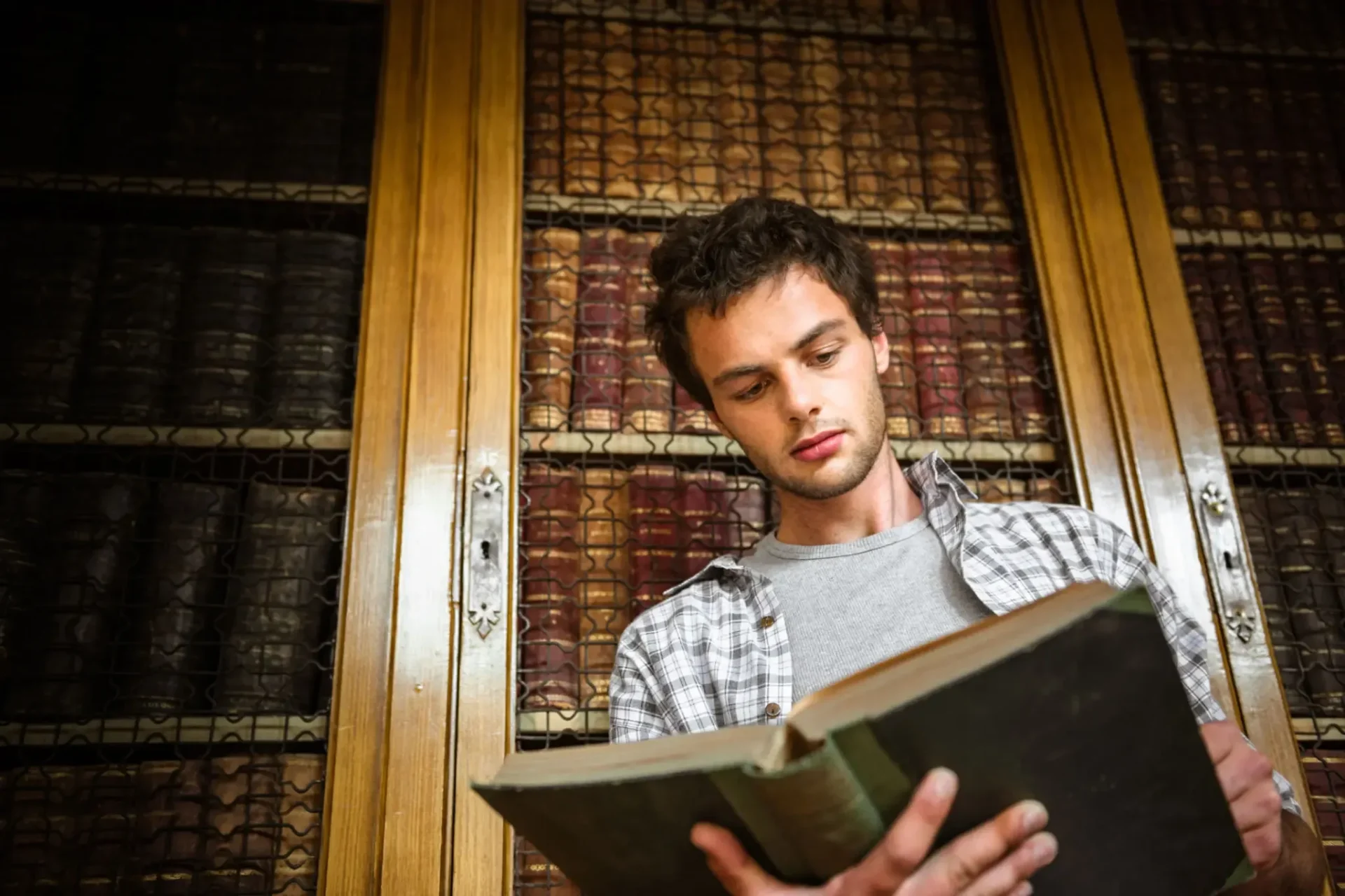 Young man reading book in antique library
