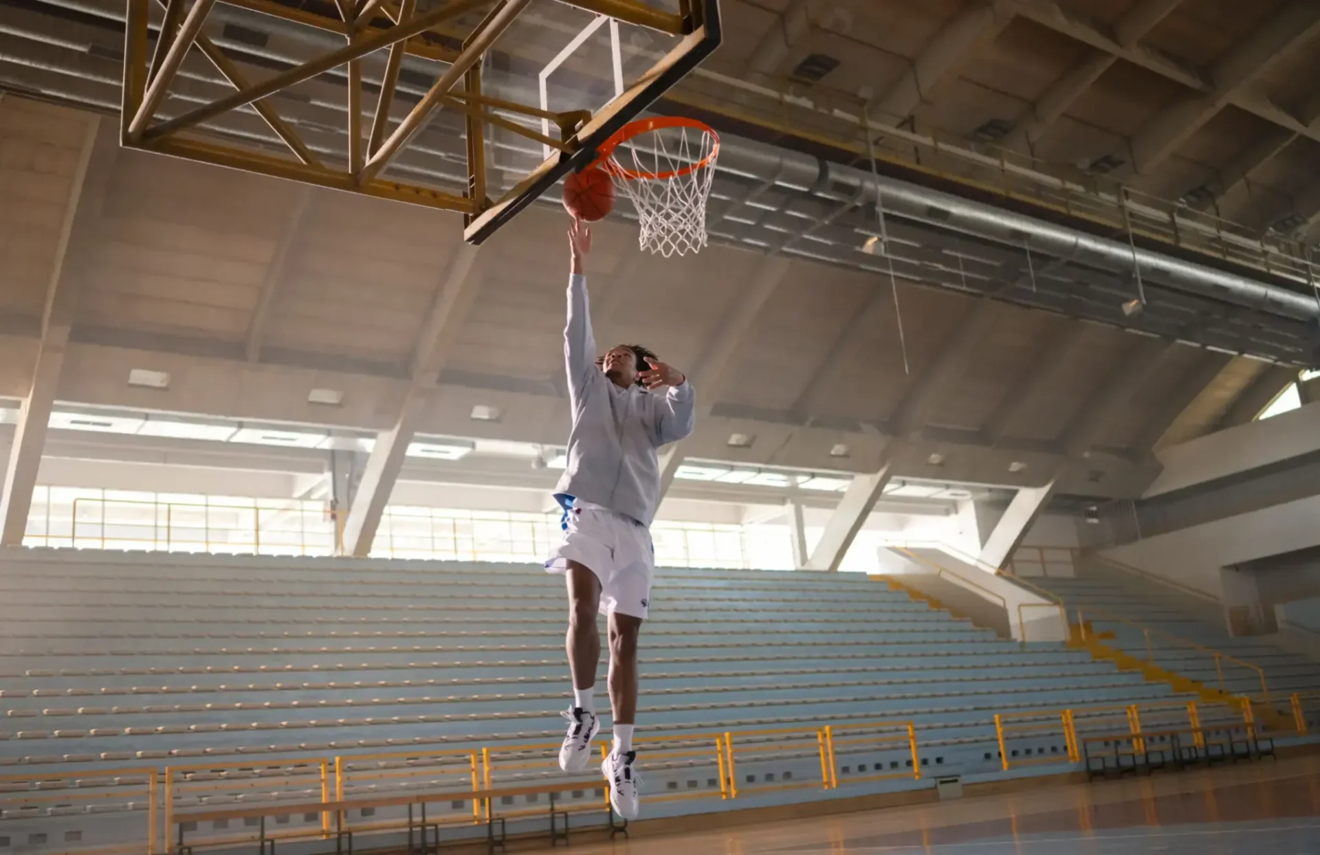 Basketball player performing dunk in empty gym