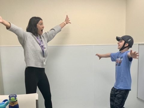 Adult and child in classroom stretching arms