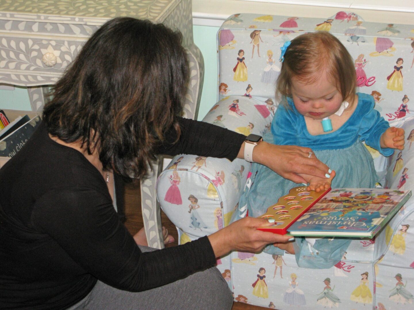Woman reading books with child on princess chair