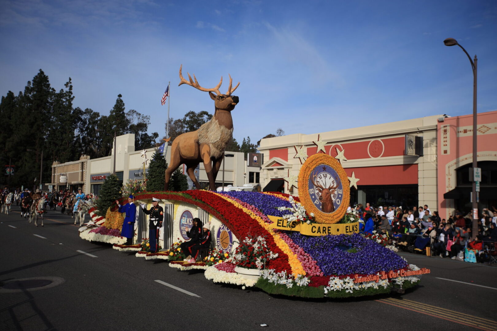 Flower-covered parade float with elk statue