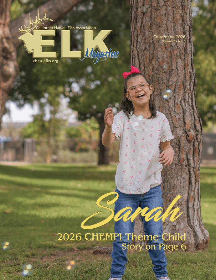 Smiling girl playing with bubbles near tree