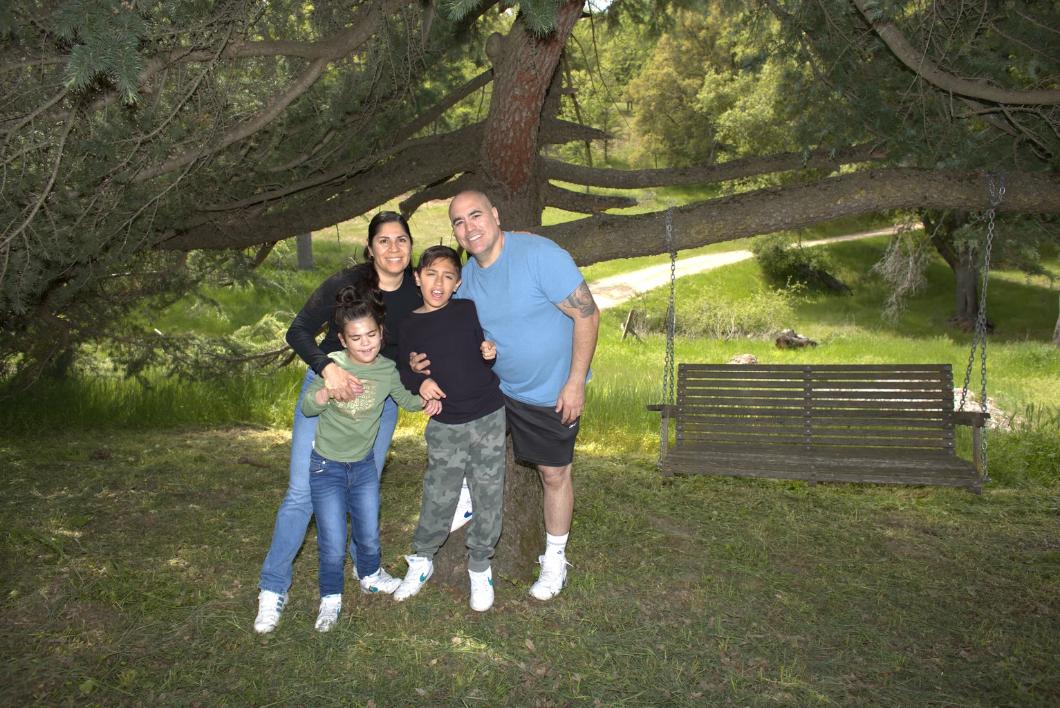 Family of four posing near tree and swing