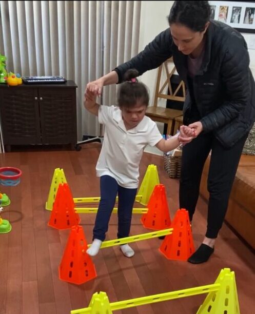 Child navigating indoor obstacle course with assistance