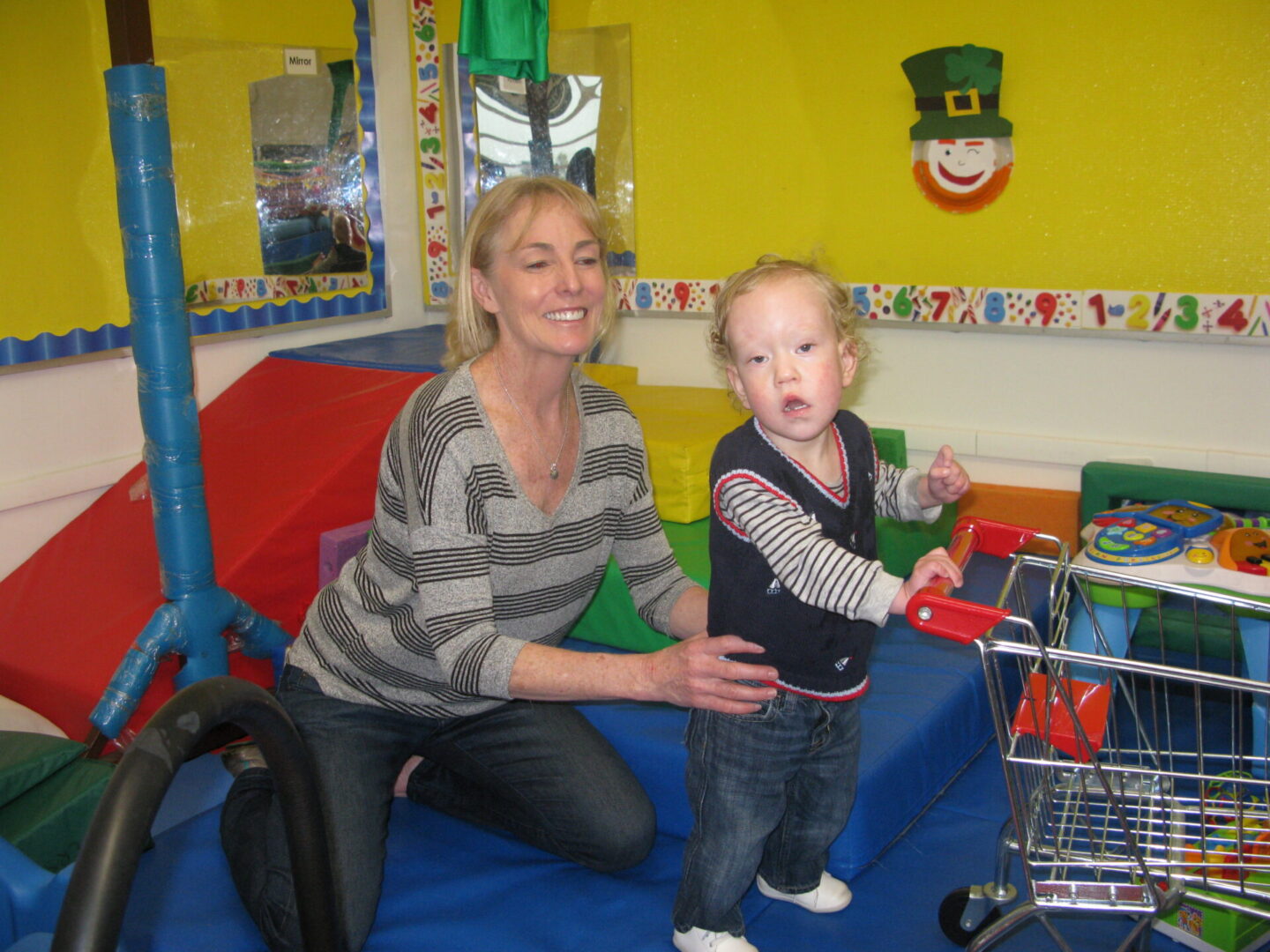 Woman and toddler playing with toy shopping cart