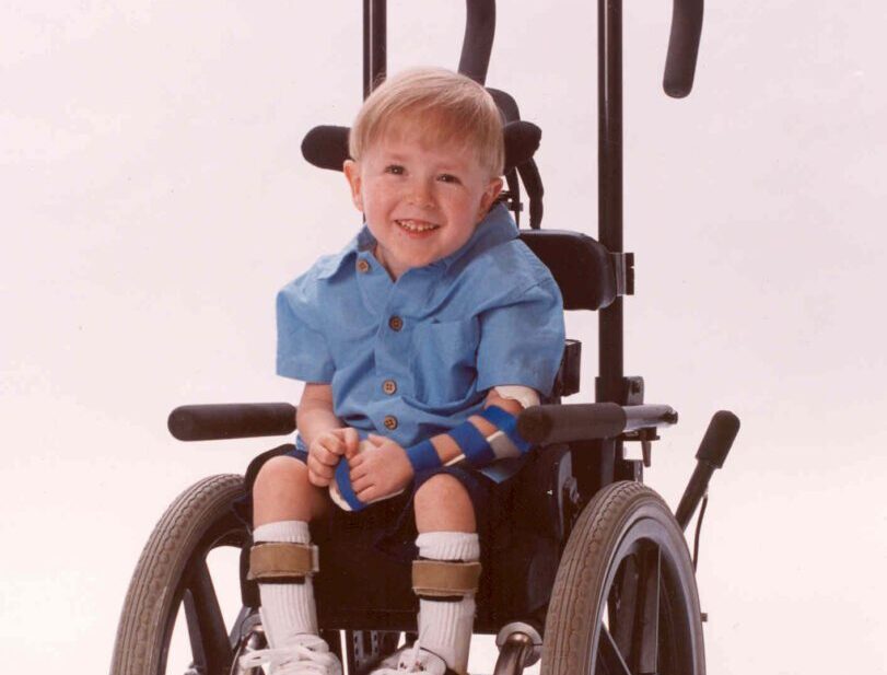 Smiling child in wheelchair wearing blue shirt