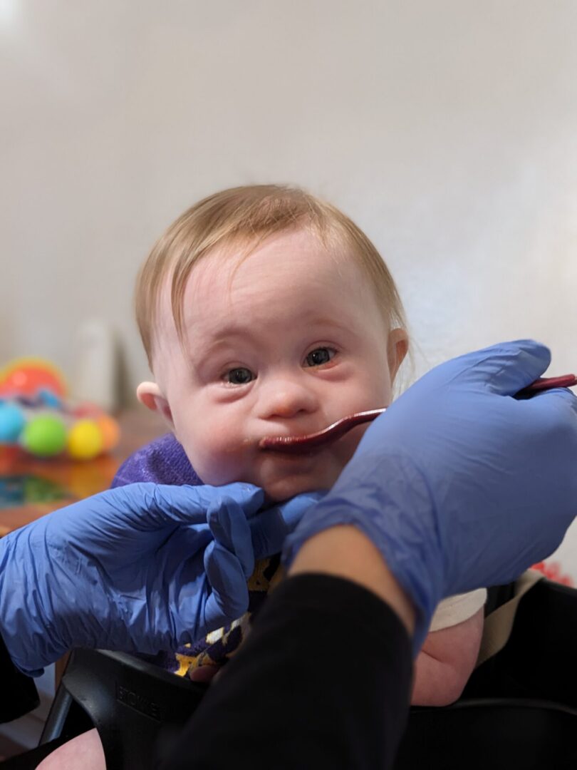 Baby being spoon-fed by gloved hands