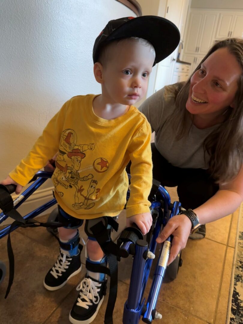 Toddler in walker with smiling caregiver