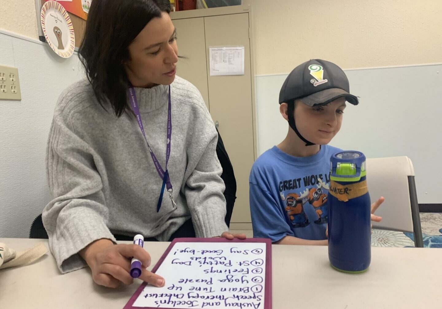 Teacher and student at table with water bottle