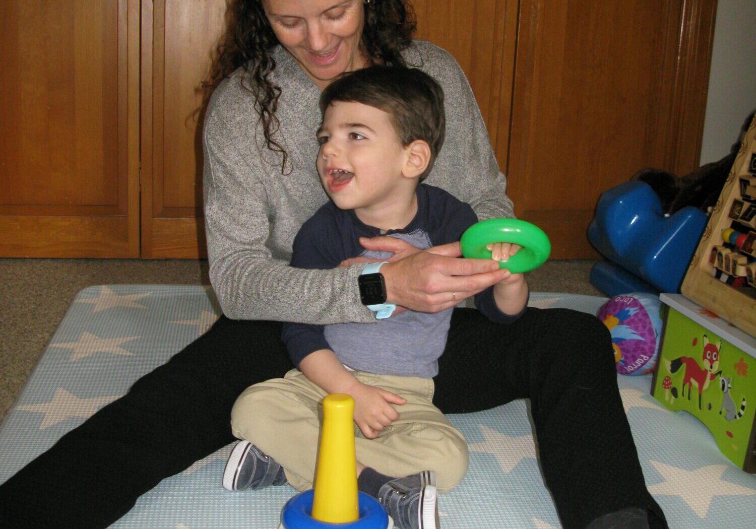 Woman and toddler play with colorful stacking rings